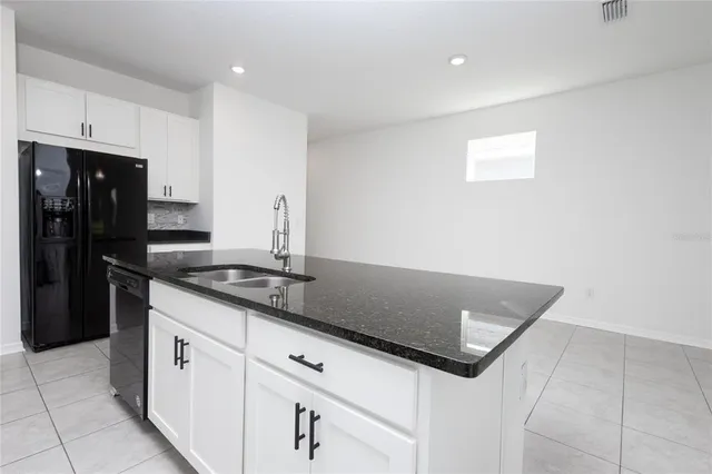 a kitchen with granite countertop white cabinets and black appliances