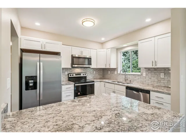 a kitchen with granite countertop a refrigerator stove top oven and sink