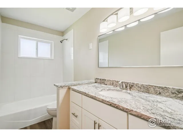 a bathroom with a granite countertop sink a mirror and a bathtub