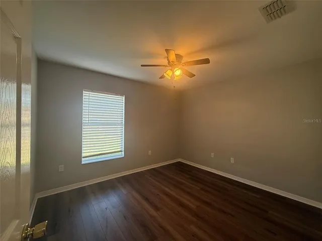 an empty room with a window and a fan