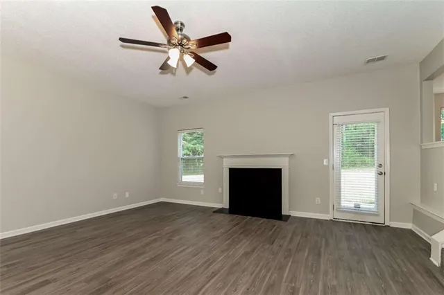 an empty room with windows fireplace and wooden floor