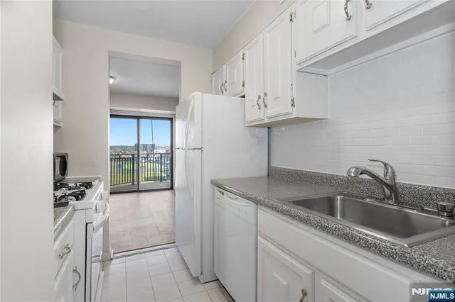 a kitchen with stainless steel appliances granite countertop a sink dishwasher and white cabinets with wooden floor