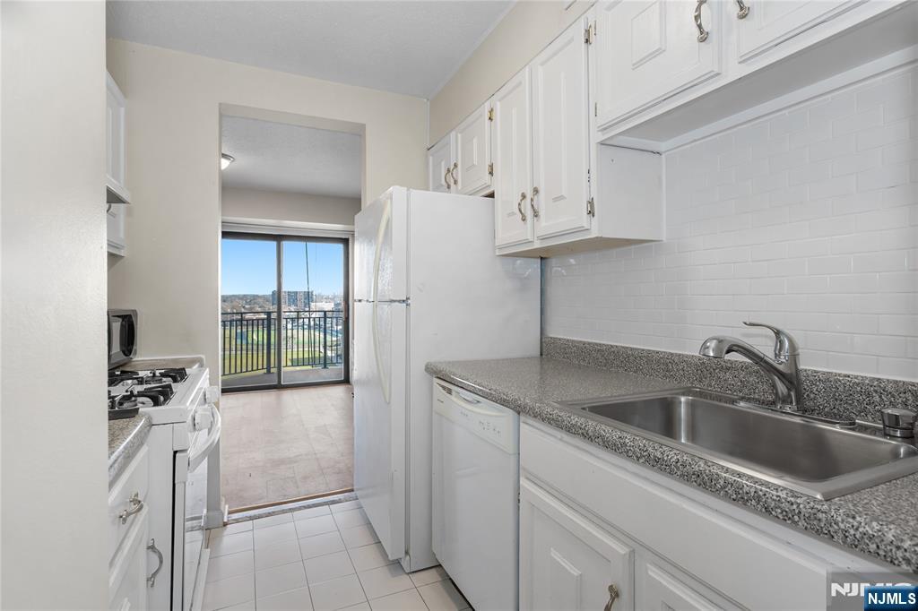 150 Overlook Avenue, Unit 6E Hackensack, NJ 07601 - Photo 10 of 30 a kitchen with stainless steel appliances granite countertop a sink dishwasher and white cabinets with wooden floor