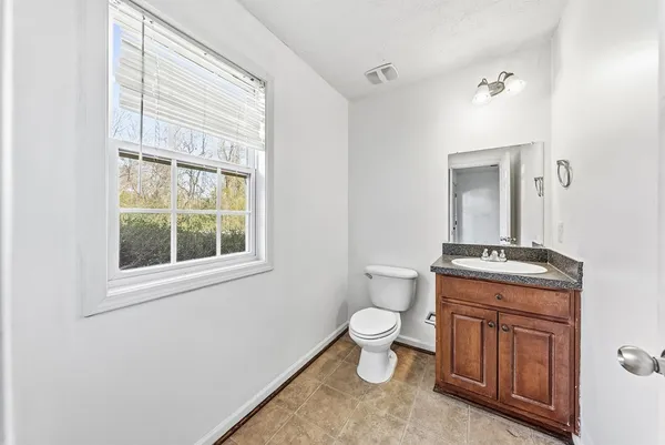 a bathroom with a granite countertop toilet a sink and a window
