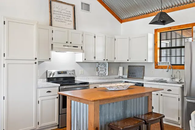 a kitchen with stainless steel appliances a stove a sink and white cabinets