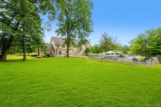 view of a swimming pool with lawn chairs and plants