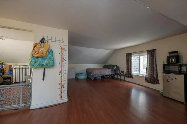 a view of an empty room with wooden floor and furniture