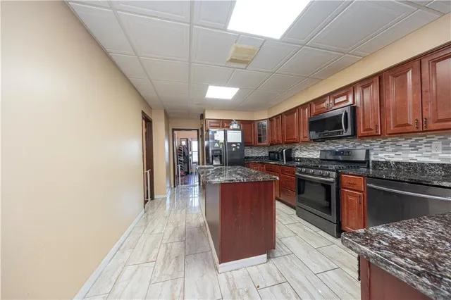 a kitchen with stainless steel appliances granite countertop a stove top oven a sink dishwasher a dining table and chairs with wooden floor