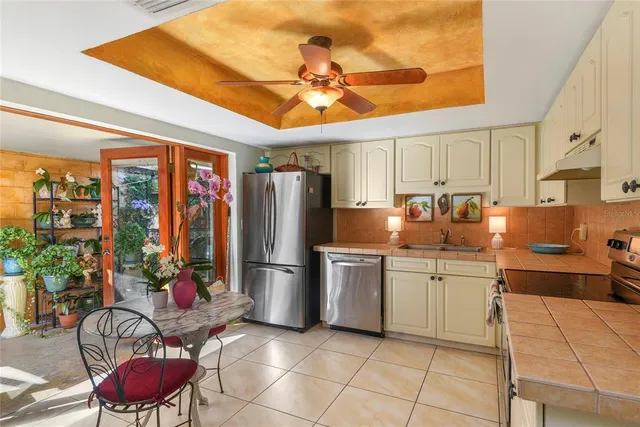 a kitchen with stainless steel appliances granite countertop a refrigerator a sink dishwasher a dining table and chairs with wooden floor