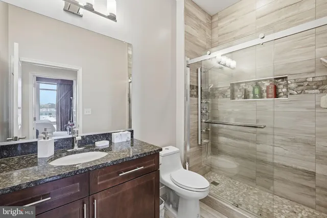 a bathroom with a granite countertop sink toilet and shower