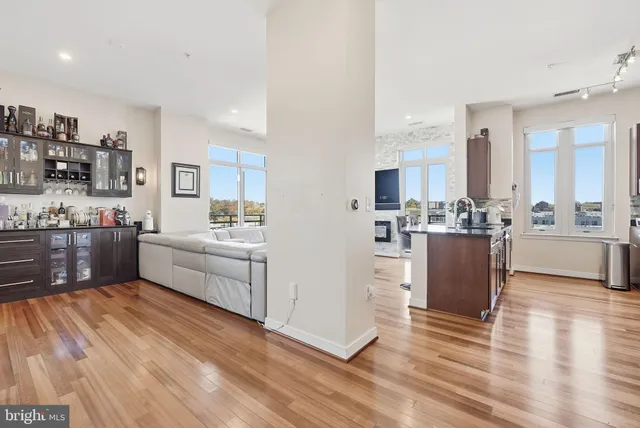 a room with stainless steel appliances kitchen island granite countertop a stove a sink a refrigerator and white cabinets with wooden floor