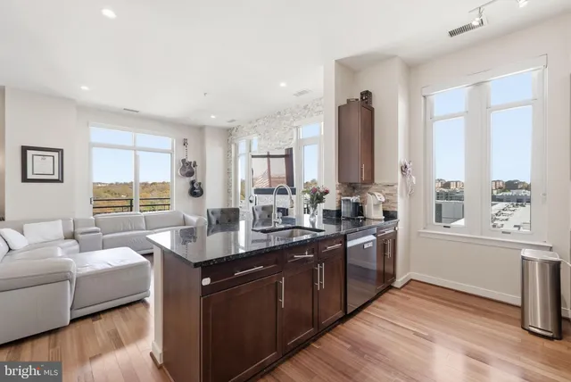 a kitchen with stainless steel appliances granite countertop a sink dishwasher a stove and a refrigerator with wooden floor