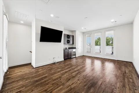 a view of a livingroom with a flat screen tv wooden floor and a ceiling fan