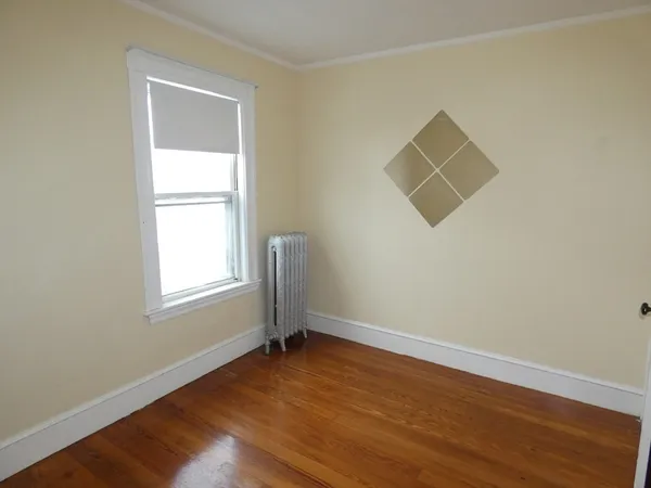 an empty room with wooden floor and a window