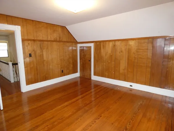 an empty room with wooden floor and entrance