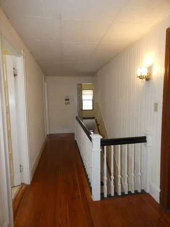 a view of a hallway with wooden floor and staircase