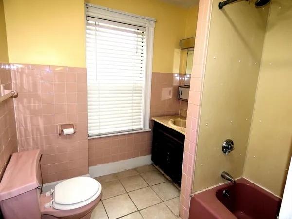 a bathroom with a sink a toilet a window and shower