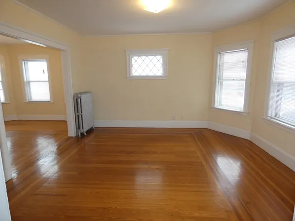 a view of empty room with wooden floor and fan