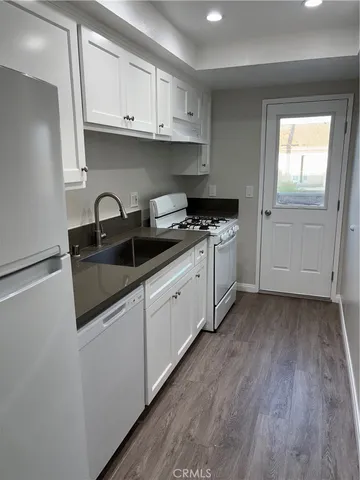 a kitchen with stainless steel appliances granite countertop a sink and cabinets with wooden floors