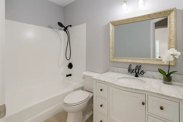 a bathroom with a granite countertop sink a toilet and a mirror