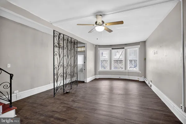 a view of an empty room with wooden floor and stairs