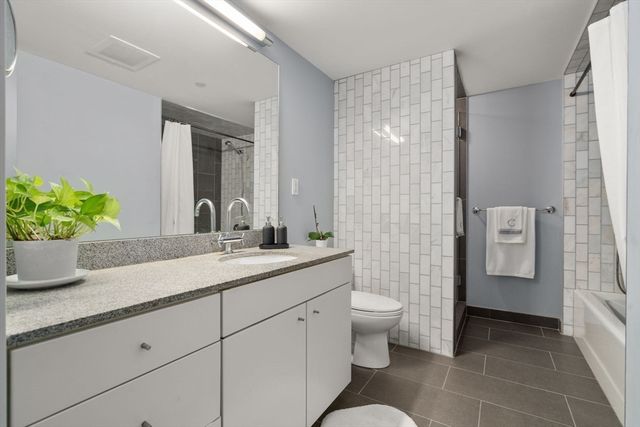 a bathroom with a granite countertop sink a toilet and shower