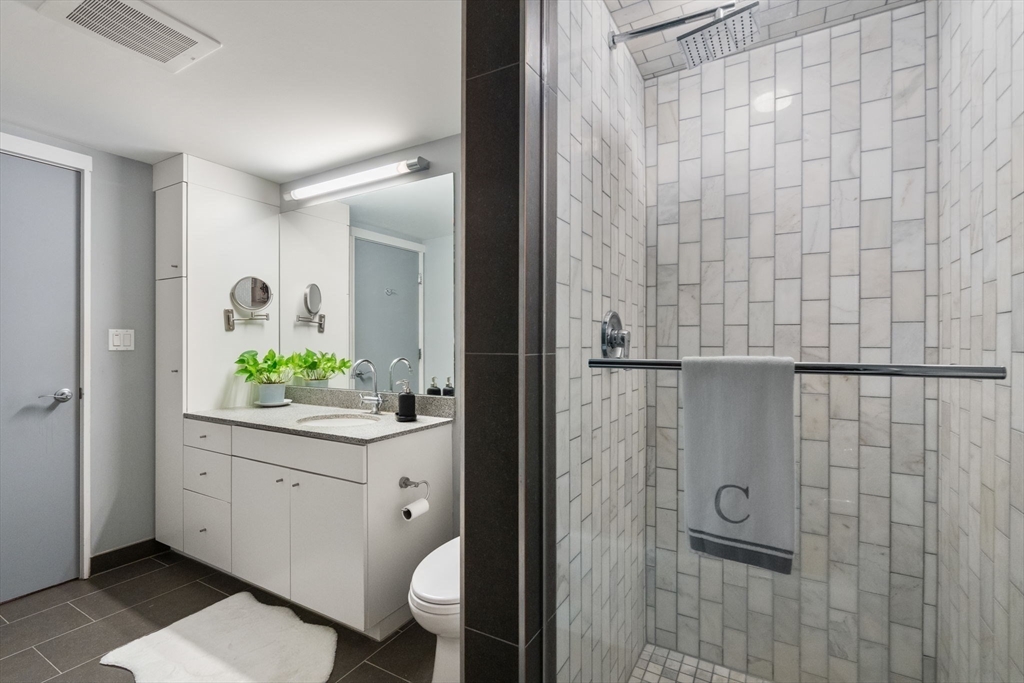 25 Channel Center Street, Unit 807 Boston, MA 02210 - Photo 19 of 27 a bathroom with a granite countertop sink a toilet and shower