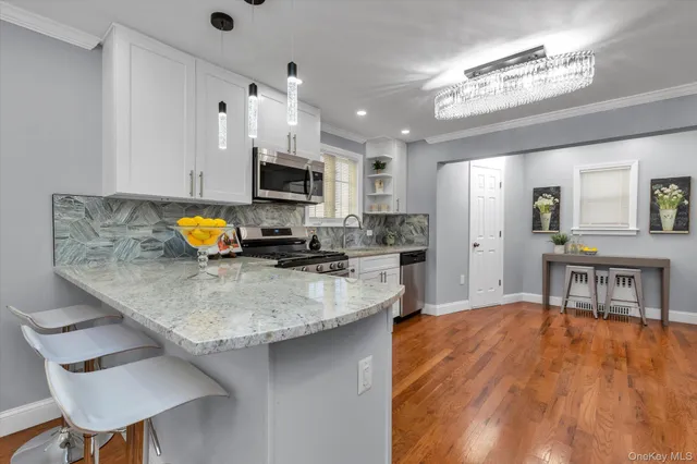 a kitchen with stainless steel appliances granite countertop a sink a stove top oven a chimney cabinets and dining table