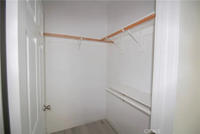 a view of an empty room with wooden floor and closet