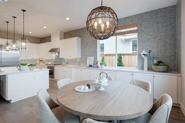 a dining room with wooden floor a chandelier a wooden table and chairs