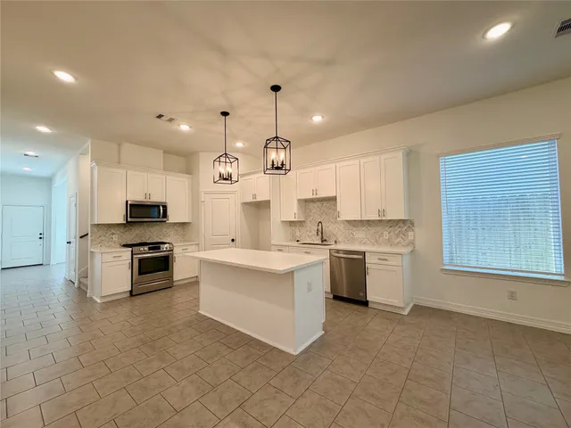 a large kitchen with cabinets in it and stainless steel appliances