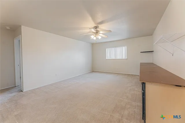 an empty room with wooden floor chandelier fan and windows