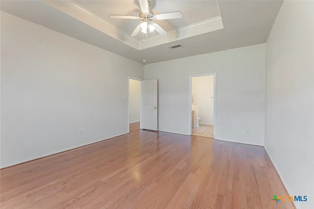 an empty room with windows and ceiling fan