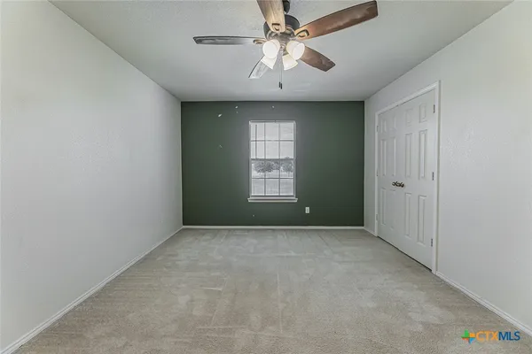 an empty room with windows and fan