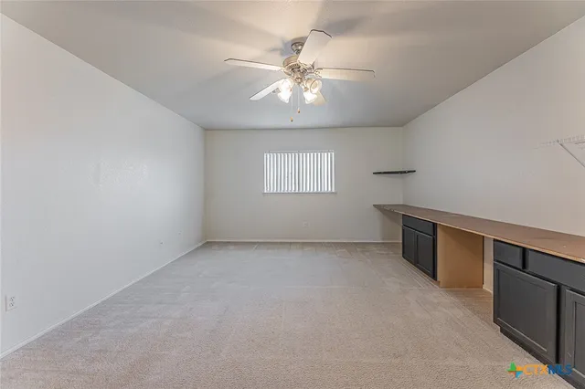 a view of an empty room with wooden floor fireplace and a window