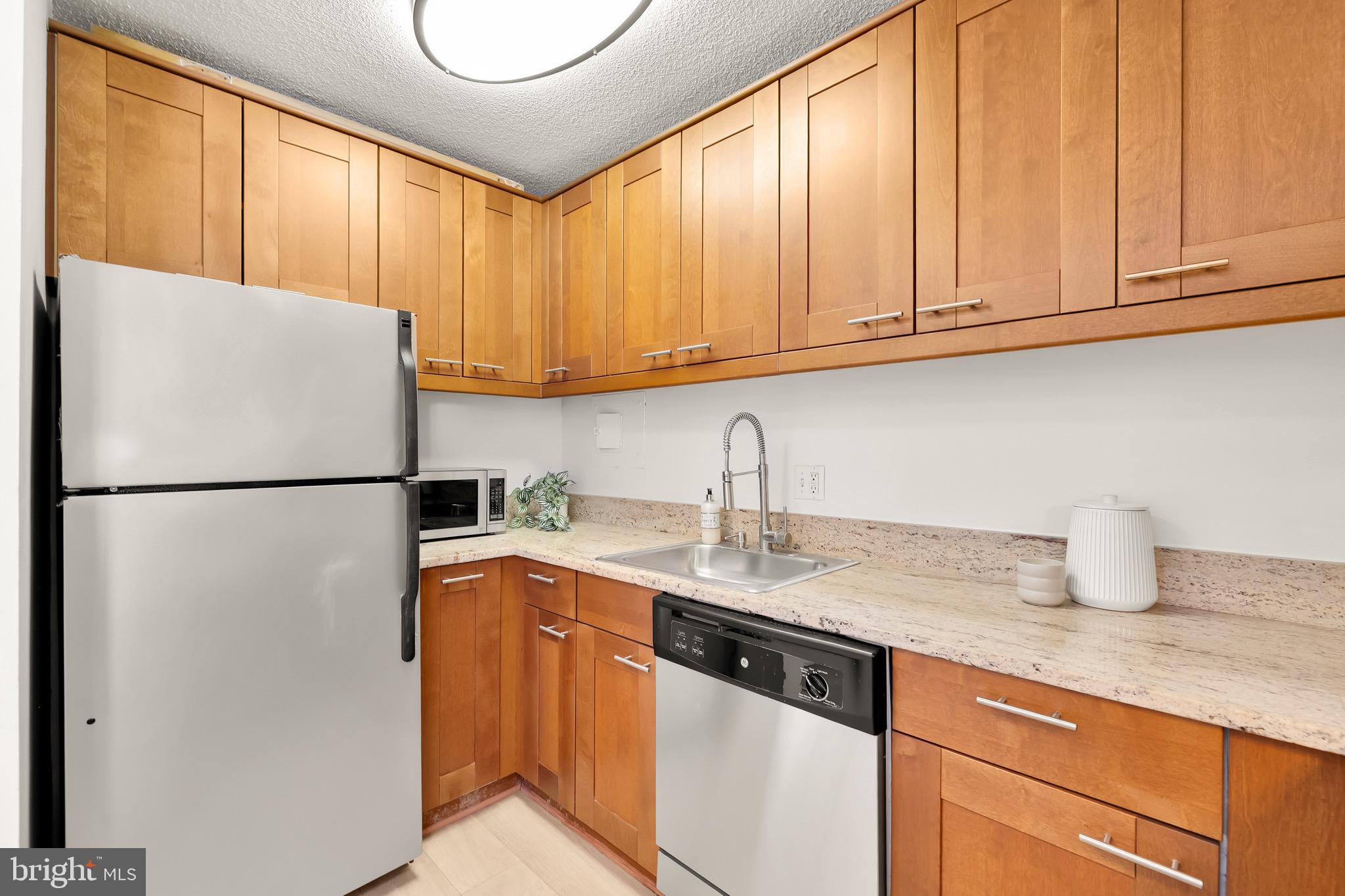 1800 R Street Northwest, Unit 807 Washington, DC 20009 - Photo 11 of 23 a kitchen with stainless steel appliances granite countertop a refrigerator sink washer and dryer