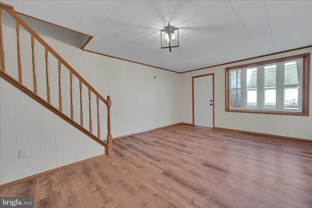 an empty room with wooden floor chandelier fan and windows