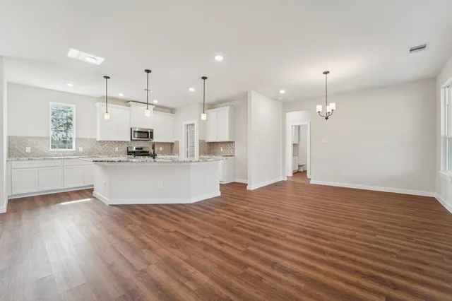 a view of kitchen with kitchen island wooden floor center island and stainless steel appliances