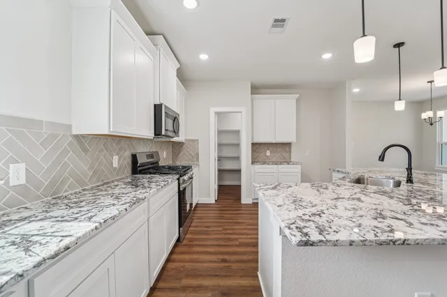 a kitchen with kitchen island granite countertop a stove and a sink