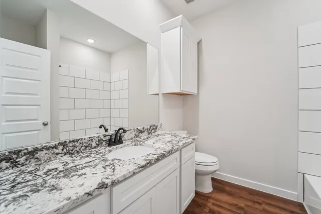a bathroom with a granite countertop sink a toilet and a shower