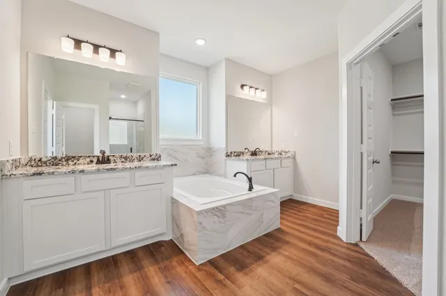 a spacious bathroom with a double vanity sink mirror and bathtub