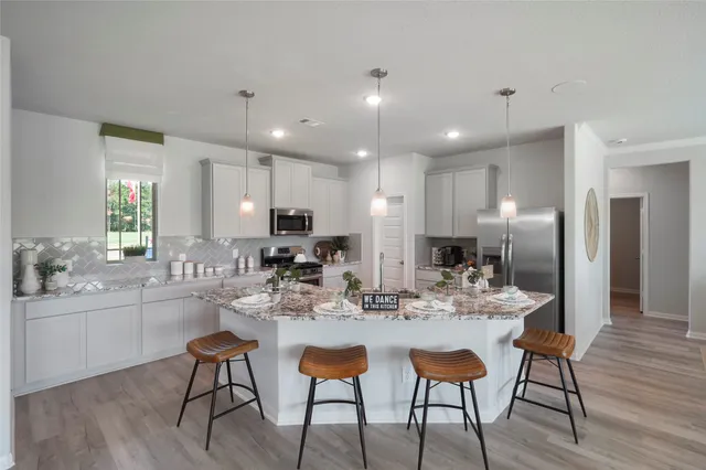 a kitchen with a dining table chairs and wooden floor