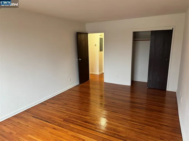 a view of an empty room with wooden floor and closet