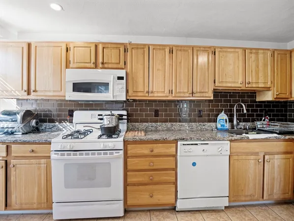 a kitchen with stainless steel appliances granite countertop a stove a sink dishwasher and cabinets with wooden floor