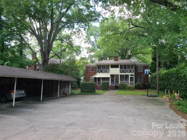a view of a house with a yard and large trees