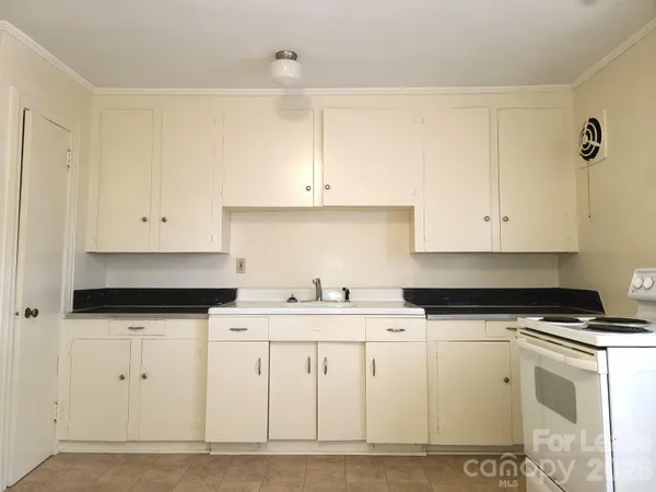 a kitchen with granite countertop a sink a stove and cabinets