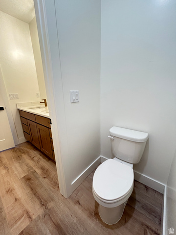 6 South 450th West Gunnison, UT 84634 - Photo 35 of 45 Contemporary powder room featuring a white toilet, wood-finish flooring, and a vanity with a white countertop and dark wood cabinetry