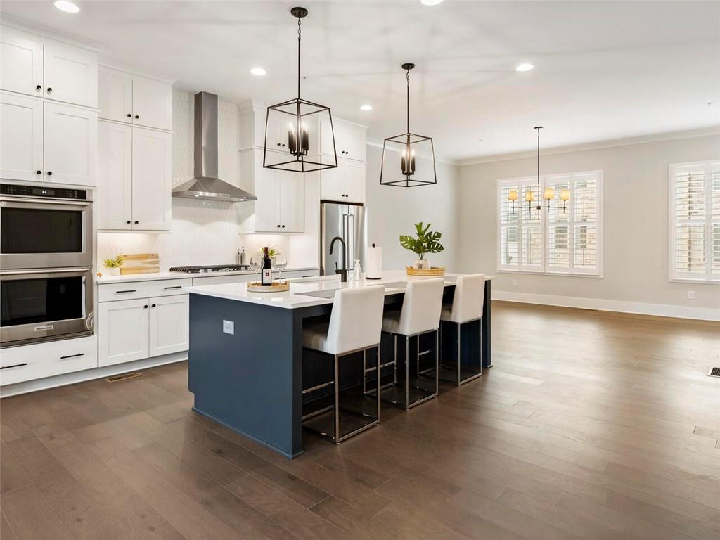 355 Chiswick Circle Alpharetta, GA 30009 - Photo 16 of 57 a large kitchen with stainless steel appliances kitchen island a large island a sink a stove and a wooden floors