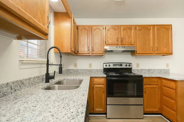 a kitchen with stainless steel appliances granite countertop a stove a sink and a microwave