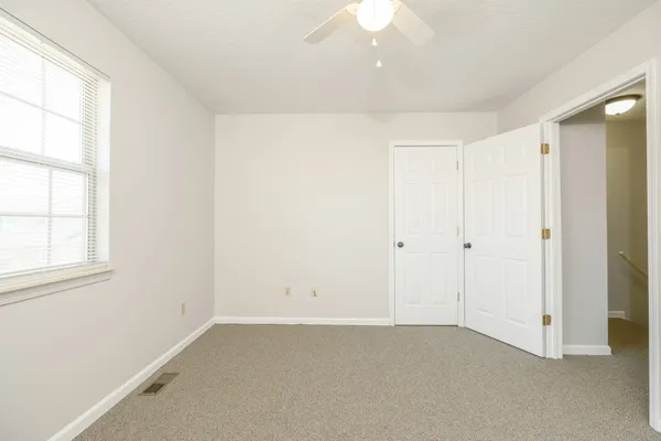 an empty room with a window and a fan